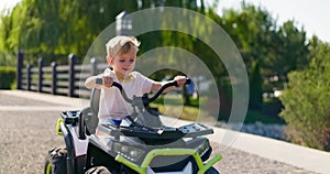 A child driving a toy electric car in a park on a summer day