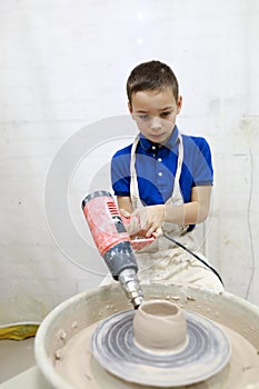 Child drying cup on pottery wheel