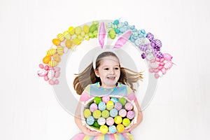 Child on Easter egg hunt. Pastel rainbow eggs.