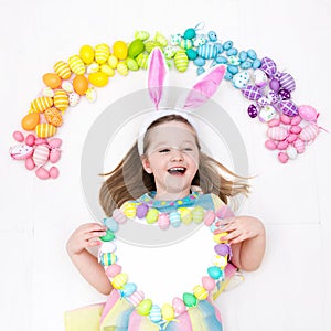 Child on Easter egg hunt. Pastel rainbow eggs.