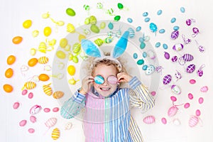 Child on Easter egg hunt. Pastel rainbow eggs.