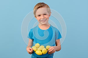 Child and Easter. Smiling blond boy, 6 years old, is holding a yellow eggs.