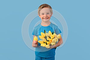 Child and Easter. Smiling blond boy, 6 years old, is holding a yellow eggs.