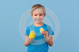 Child and Easter. Smiling blond boy, 6 years old, is holding a yellow eggs.