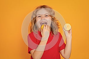 Child eat lemon in studio. Studio portrait of cute kid boy lick lemon isolated on yellow.