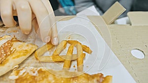 Child eat pizza and french fry potato. Close up of young girl woman eating pizza and chewing in outdoor restaurant.