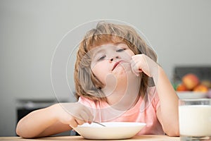 Child eat. Unhappy Caucasian child sit at table at home kitchen have no appetite. Upset little kid refuse to eat organic