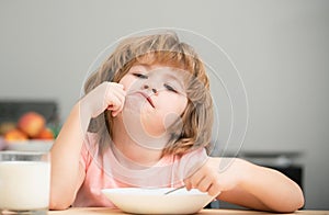 Child eat. Unhappy Caucasian child sit at table at home kitchen have no appetite. Upset little kid refuse to eat organic