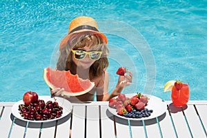 Child eat watermelon. Healthy kids and summer vacation. Kid with summer fruits in pool. Child in swimming pool playing