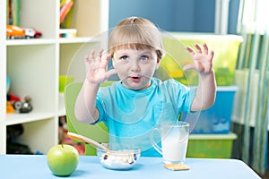 Child eating apple at dinner in nursery at home