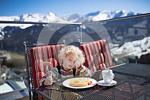 Child eating apres ski lunch. Winter snow fun for kids.