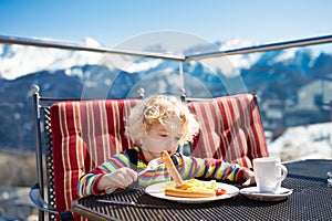 Child eating apres ski lunch. Winter snow fun for kids.