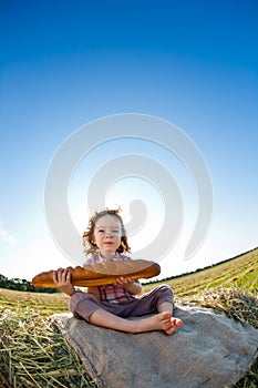 Child eating bread in wheat field