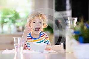 Child eating breakfast. Kid with milk and cereal