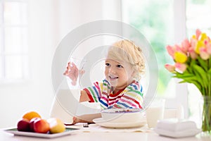 Child eating breakfast. Kid with milk and cereal