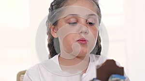 child eating chocolate. unhealthy a food for children sweets concept. grimy girl eating a chocolate bar in the kitchen