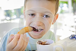 A child eating churros with chocolate