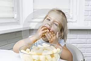 Child eating corn sticks at the kitchen table