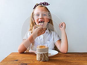 Child eating crispbread peanut butter sitting at table in kitchen at home. Nutritious superfood vegan healthy lifestyle