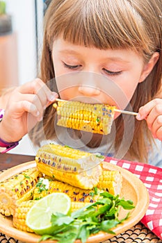 Child eating delicious grilled corn
