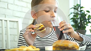 Child eating fast food, kid eats hamburger in restaurant, girl drinking juice