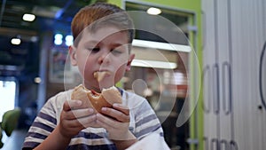 Child eating food for dinner, french fries and burger for lunch for schoolboy, male child eats hamburger and french