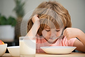 Child eating healthy food at home. Unhappy child have no appetite. Upset little kid refuse to eat organic cereals with