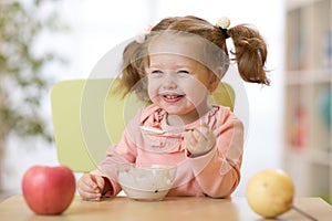 Child eating healthy food with the left hand at home