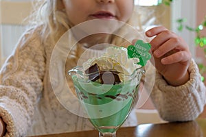 Child eating an ice cream sundae treat for St. Patrick`s Day