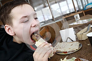Child eating lula kebab in pita