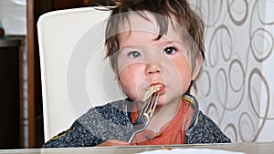 Child eating pasta at the table with a fork