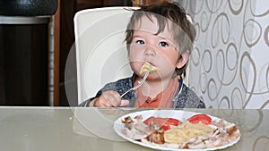 Child eating pasta at the table with a fork