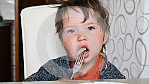 Child eating pasta at the table with a fork