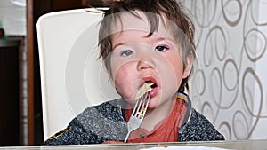 Child eating pasta at the table with a fork. Lunch in a child 1-2 years