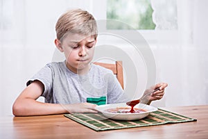 Child eating soup with disgust photo