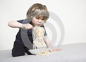 Child eating spaghetti on the sofa