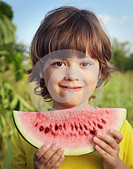 child eating watermelon in the garden