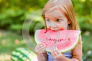 Child eating watermelon in the garden. Kids eat fruit outdoors. Healthy snack for children. 2 years old girl enjoying watermelon