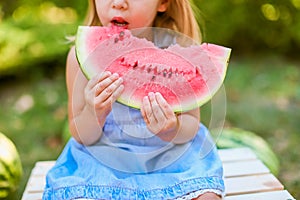 Child eating watermelon in the garden. Kids eat fruit outdoors. Healthy snack for children. 2 years old girl enjoying watermelon