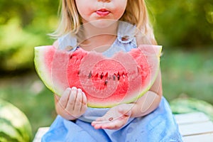 Child eating watermelon in the garden. Kids eat fruit outdoors. Healthy snack for children. 2 years old girl enjoying watermelon