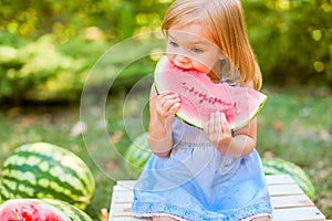 Child eating watermelon in the garden. Kids eat fruit outdoors. Healthy snack for children. 2 years old girl enjoying watermelon