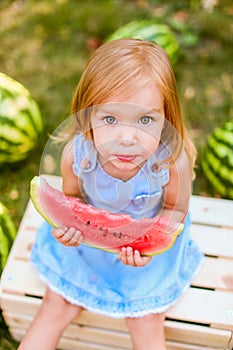 Child eating watermelon in the garden. Kids eat fruit outdoors. Healthy snack for children. 2 years old girl enjoying watermelon