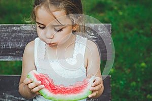 Child eating watermelon in the garden. Kids eat fruit outdoors. Healthy snack for children. Beautiful background, emotion girl