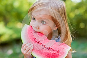 Child eating watermelon in the garden. Kids eat fruit outdoors. Healthy snack for children. 2 years old girl enjoying watermelon