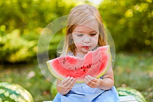 Child eating watermelon in the garden. Kids eat fruit outdoors. Healthy snack for children. 2 years old girl enjoying