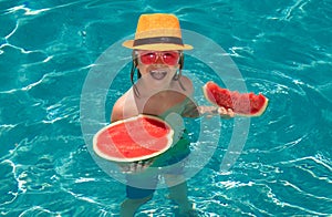 Child eating watermelon. Kid having fun in swimming pool. Summer vacation and healthy lifestyle concept. Kids eat fruit