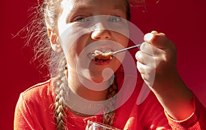 Child eating yogurt jelly on pink background. Dairy products kids diet, healthy homemade breakfast menu. Kids healthcare