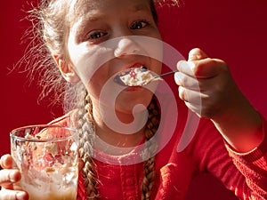 Child eating yogurt jelly on pink background. Dairy products kids diet, healthy homemade breakfast menu. Kids healthcare