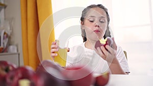 the child eats an apple and drinks juice. healthy eating fruit concept. child brunette girl eating an apple on the table