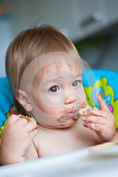 Child eats cake in the highchair